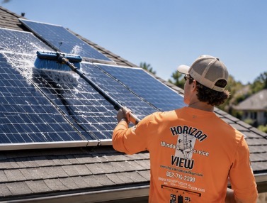 Horizon View technician in orange uniform cleaning rooftop solar panels