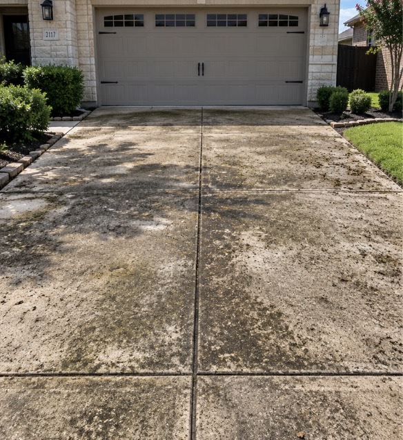 Discolored, tire marked and oil stained concrete driveway at a Plano TX home before pressure washing